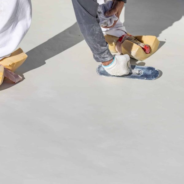 Worker Wearing Sponges On Shoes Smoothing Wet Pool Plaster With Trowel.